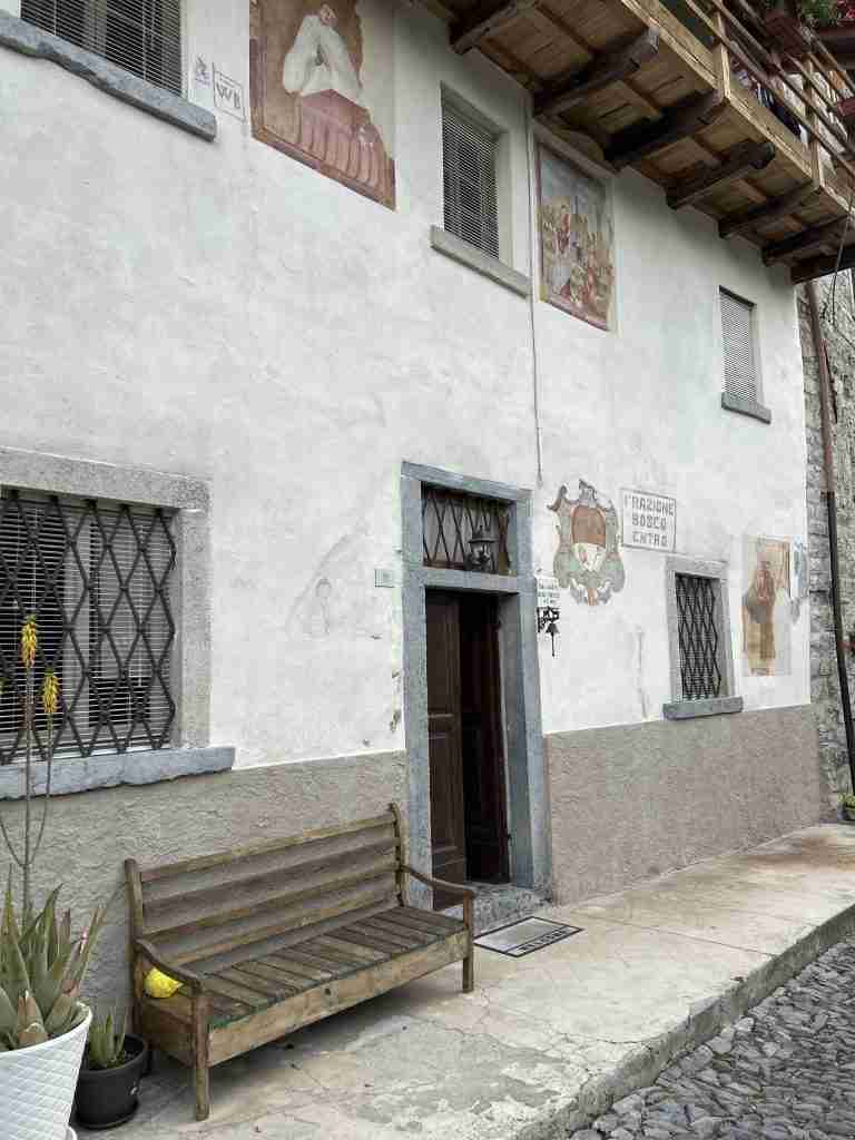 Accesso a Bosco Entro ex casa Curato con insegna e affreschi dei Santi